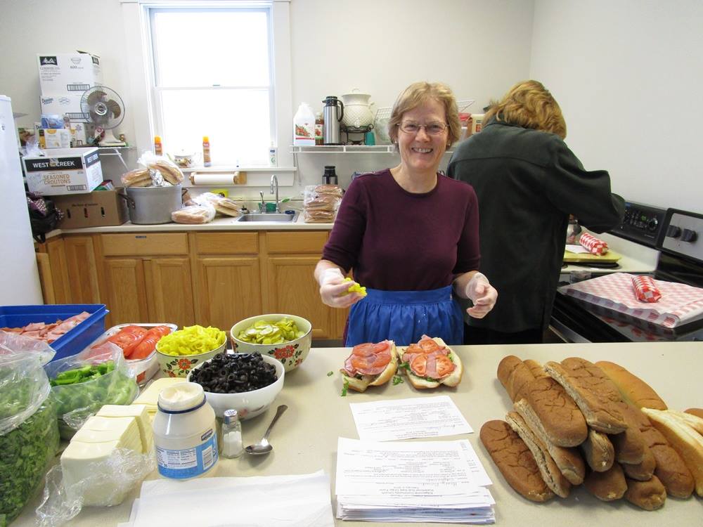 A smiling woman preparing sandwiches